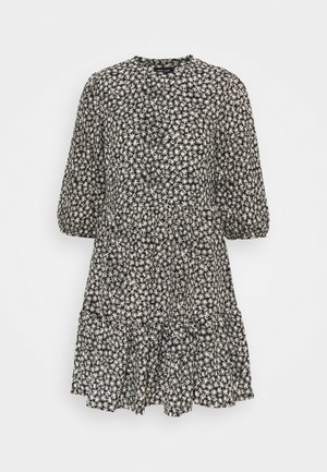 Robe noire avec motif floral blanc, encolure ronde, manches 3/4 bouffantes, et ourlet à volants à plusieurs niveaux. Tissu léger, adapté à diverses occasions.