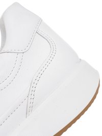 Close-up of white leather sneaker heel with detailed stitching and white sole featuring a brown rubber outsole.