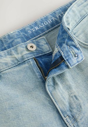 Hellblaue gerade geschnittene Denim-Jeans mit einem Reißverschluss, Metallknopfverschluss und kontrastierenden Nähten, die eine weiche, ausgeblichene Textur aufweisen.