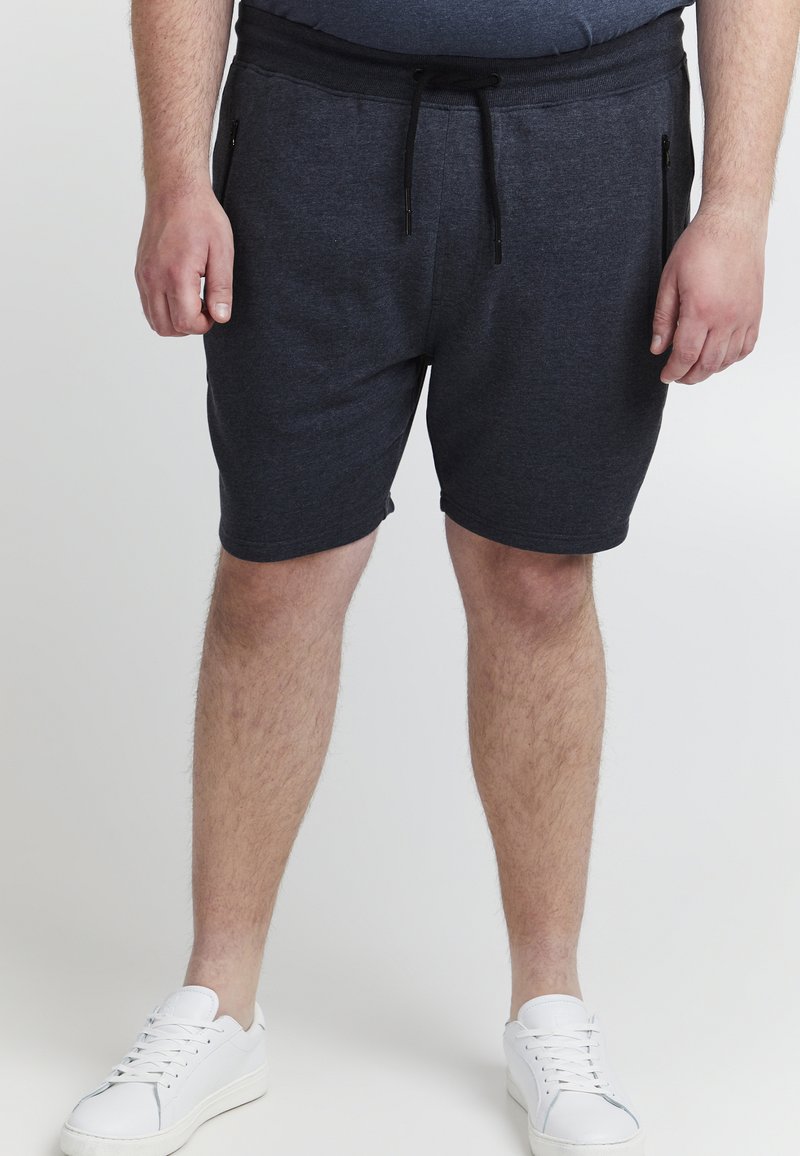 Shorts gris foncé avec taille élastique et cordon de serrage ajustable, dotés de deux poches latérales zippées et en tissu doux et texturé.