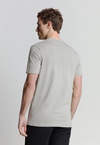 Lichtgrijze T-shirt met korte mouwen met een subtiel streepjespatroon, ronde halslijn en zachte stof. Draagt door een persoon die van je af kijkt.