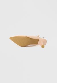 Visoko peto z ostrim prstom, zgornji del iz gole usnjene kože, bež podplat in gumijasti nasvet na peti za stabilnost. Teksturiran oprijem na podplatu.