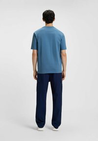 T-shirt azzurro a maniche corte realizzato in tessuto morbido, abbinato a pantaloni cargo blu navy con tasche laterali e vestibilità morbida.
