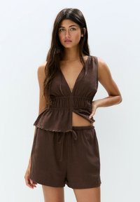 Brun linne tvådelad outfit bestående av en ärmlös topp med V-ringning och elastisk midja, tillsammans med korta shorts med dragsko.
