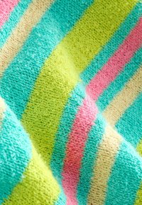 Tissu doux et texturé avec des rayures diagonales dans des couleurs pastel turquoise, vert citron, rose et crème, montrant des plis et des ombres.
