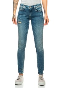 Smala blå denimjeans med slitna detaljer vid knäna och fickorna. Har en knappstängning och femficksdesign. Litet stretchigt tyg.