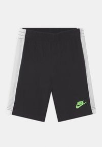 Pantaloni sportivi neri con una cintura elastica, pannelli laterali in rete bianca e un logo Nike verde sul lato inferiore sinistro.