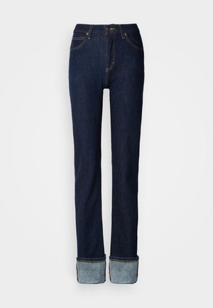 Tmavomodré riflové nohavice s rovnými nohavicami, ktoré majú stáčaný lem a kontrastné šitie. Stredne vysoký pás s klasickým zapínaním na gombík.