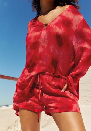 Červený tie-dye top s výstřihem do V a šortkami s elastickým pasem. Lehký materiál, volný střih, s šňůrkou a dekorativními detaily.