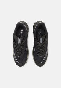Zapatillas deportivas negras con parte superior de malla, cordones negros texturizados y acentos reflectantes. Cuentan con una suela acolchada para mayor comodidad.