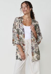 Kimono de tela ligera con estampado floral, que presenta mangas anchas y un frente abierto. Los colores suaves incluyen beis, verde y acentos naranjas.