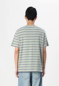 Camiseta verde a rayas con líneas horizontales en blanco y azul marino. Manga corta, cuello redondo, material de algodón. Corte relajado y textura suave.