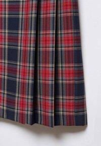 Jupe plissée en tartan présentant un motif à carreaux bleu, rouge et jaune, en tissu texturé avec un tombé structuré.