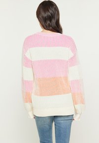 Gebreide trui in crèmekleur met roze en oranje strepen. Kenmerkt zich door een oversized pasvorm, lange mouwen en ribbelstructuur. Rechte zoom aan de onderkant.