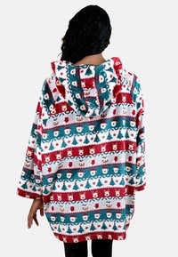 Rode en teal bedrukte capuchondeken met een pluche, zachte textuur, versierd met kerstmotieven van de kerstman, bomen en rendieren in gestreepte patronen.