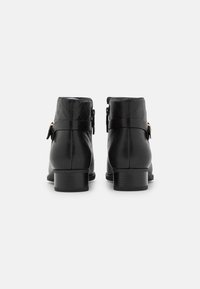 Botines de cuero negro con un patrón texturizado, punta redonda, tacón bloque de altura media y una correa con un detalle de hebilla de metal.