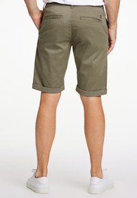 Pantaloni corti verde oliva con risvolti, realizzati in tessuto leggero. Presentano due tasche posteriori e un piccolo cartellino del marchio sulla cintura.