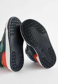 Sneakers w mieszance granatu, zieleni, czerwieni i bieli. Teksturowane gumowe podeszwy z geometrycznymi wzorami. Gładka skórzana i tkaninowa konstrukcja cholewki.