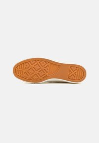 Rubber sole with a textured orange bottom and white edge. Features a diamond pattern and logo detail, designed for grip and durability.