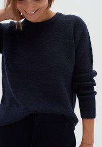 Tumed sinine kootud sviiter pehme, tekstuurse viimistlusega, sooniku kaelusega ja veidi rullitud varrukatega. Sirge alläär.