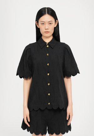 Cămașă neagră cu mâneci scurte și tiv ondulat, având nasturi aurii, material texturat și guler clasic. Asortată cu pantaloni scurți în aceeași nuanță.