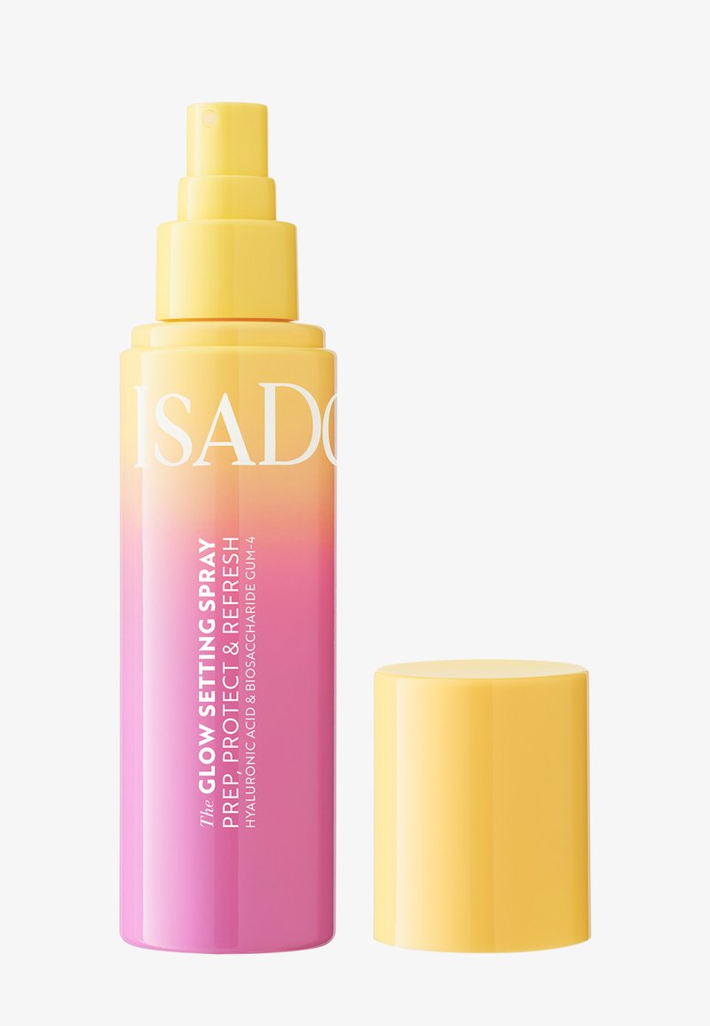 Sprayflaske i gul og rosa gradient merket Glow Setting Spray Prep, Protect & Refresh med løsnet gul hette på hvit bakgrunn.