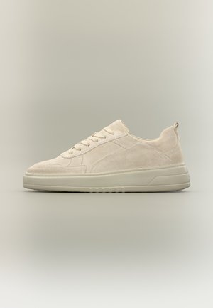 Beiger Wildleder-Sneaker mit niedrigem Schaft, Schnürung vorne und dicker Gummisohle vor neutralem Hintergrund.