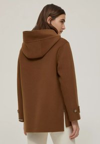 Cappotto marrone con cappuccio realizzato in misto lana, caratterizzato da una linea dritta, polsini con bottone e spacco laterale per facilitare il movimento. Design semplice e pulito.