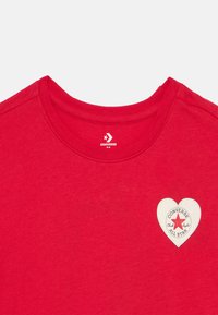 Κόκκινο βαμβακερό t-shirt με στρογγυλή λαιμόκοψη και λευκή καρδιά-σχήματος επιφάνεια με κόκκινο αστέρι και το κείμενο «Converse All Star».