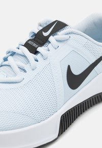 Svijetloplavi atletski tenisice s mrežastim gornjim dijelom, crnim Nike swooshom, bijelim potplatom i teksturiranim detaljima. Dizajn naglašava prozračnost i potporu.
