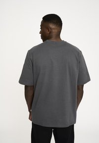 Grå bomulds T-shirt med rund hals, korte ærmer og afslappet pasform. Glat tekstur og ingen synlige mønstre eller hardware-detaljer.