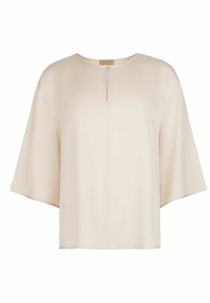 Løs beige bluse med brede trekvartlange ærmer og en lille frontnøglehulsdetalje med enkelt knaplukning.