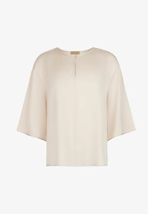 Løs beige bluse med brede trekvartlange ærmer og en lille frontnøglehulsdetalje med enkelt knaplukning.