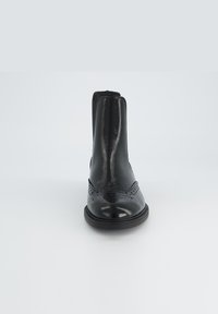 Botas de cuero negro hasta el tobillo con un acabado pulido, que cuentan con detalles de brogue, paneles laterales elásticos y una suela baja de goma.