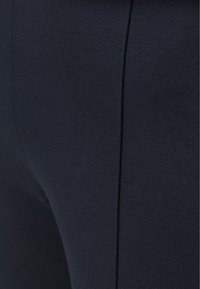 Leggings bleu marine en tissu lisse et extensible. Présente un design ajusté avec une silhouette simple et épurée sans motifs ni accents visibles.