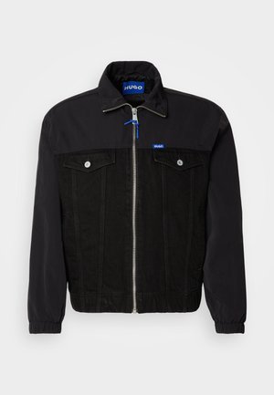Black jacket featuring a denim lower section and nylon upper. Front zip closure, two chest pockets, and elastic cuffs. Logo tag on collar.