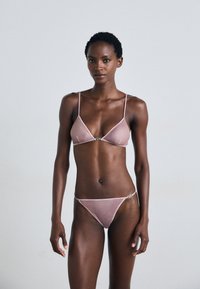 Roze satijnen lingerieset met een driehoekige bralette en een thong. Verstelbare bandjes en een zilveren accentdetail op de tailleband.