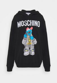 Sweat à capuche noir avec le texte "MOSCHINO" et un personnage de dessin animé bleu portant une casquette rouge, un survêtement gris, une chaîne en or, tenant un cookie.