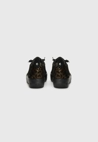 Black sneakers with a leopard print suede upper, textured black back, and round silver eyelets for laces. Soft material with a glossy finish.