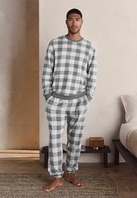 Grau-weißer Karopajamasatz mit langen Ärmeln und elastischem Bund, aus weichem Stoff gefertigt, mit lockerem Schnitt und gerippten Bündchen.