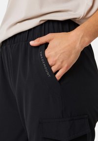 Black pants made of lightweight fabric with an elastic waistband, featuring side pockets and a visible logo "SWEDMOUNT" on the pocket.