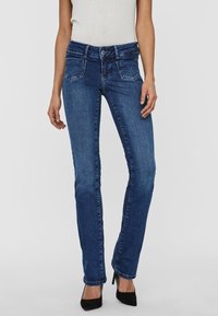 Mörkblå jeans i denim med en smal rak skärning, med medelhög midja, fem fickor och en klassisk knappgylf.