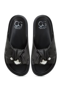 Sandali slides in pelle nera con design annodato e due accenti di cristallo sul davanti. Presentano una soletta testurizzata e una superficie esterna liscia.