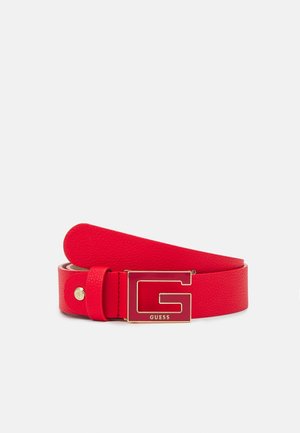 Rode leren riem met textuur en een grote gouden en rode "G" gesp met de tekst "GUESS" op een witte achtergrond.