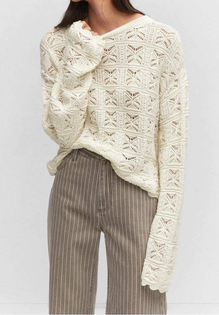 Pull en tricot crème avec un motif géométrique, manches longues aux bords festonnés, associé à un pantalon beige rayé taille haute.