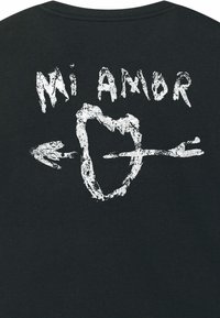 Zwarte T-shirt met een grafisch ontwerp met de tekst "Mi Amor" en een pijl die door een hartvorm steekt.