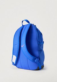 Μπλε σακίδιο πλάτης από νάιλον με καμπυλωτό σχήμα, επενδυμένους ιμάντες ώμου, ροζ λογότυπο και πλαϊνή τσέπη, με ανθεκτική, υφή επιφάνεια.