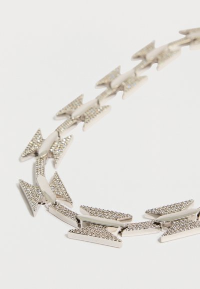 Srebrna ogrlica z elementi v obliki puščice, okrašena z majhnimi bleščečimi kamni. Oblika je elegantna s poliranim zaključkom.