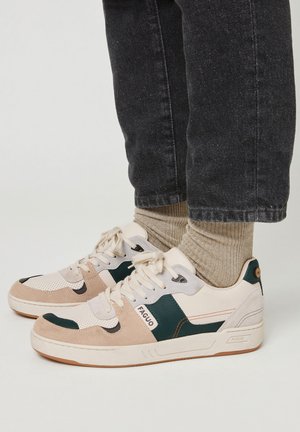 Sneaker beige e verdi realizzati in suede e mesh, con una superficie testurizzata, punta rotonda, lacci e logo del marchio sul lato.