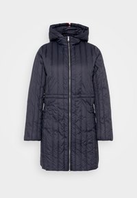 Abrigo acolchado largo en azul marino con capucha y cremallera frontal, diseñado para proporcionar calidez y protección contra el clima.